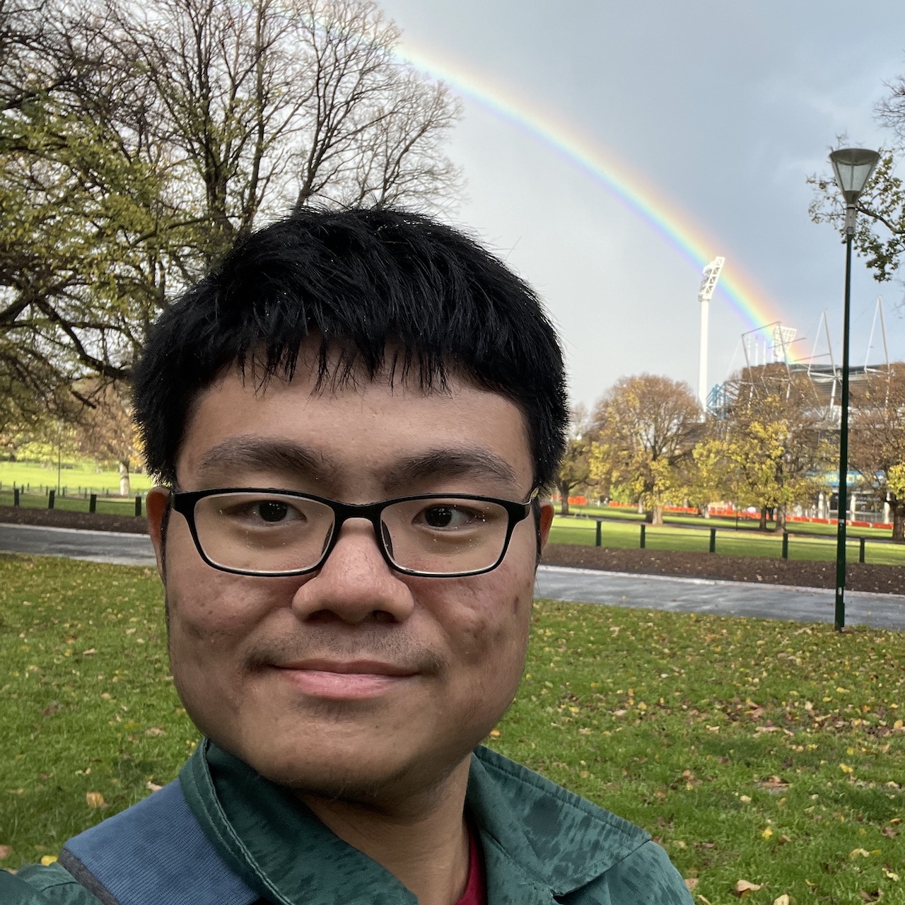 A selfie of me with a rainbow in a park.